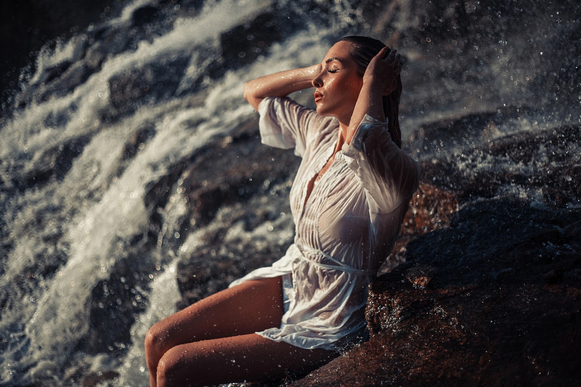 charming woman sitting on the rock near ocean